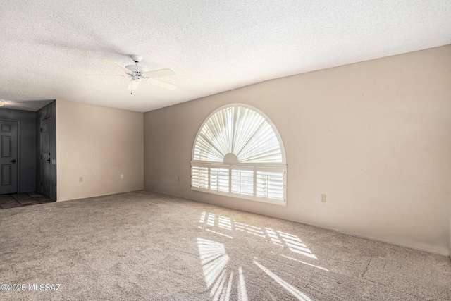 spare room with a textured ceiling, ceiling fan, and carpet