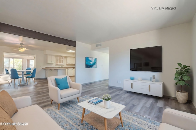 living room with ceiling fan, beam ceiling, and light hardwood / wood-style floors