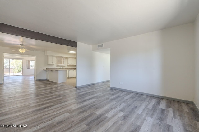 unfurnished living room with light hardwood / wood-style floors, ceiling fan, and beamed ceiling