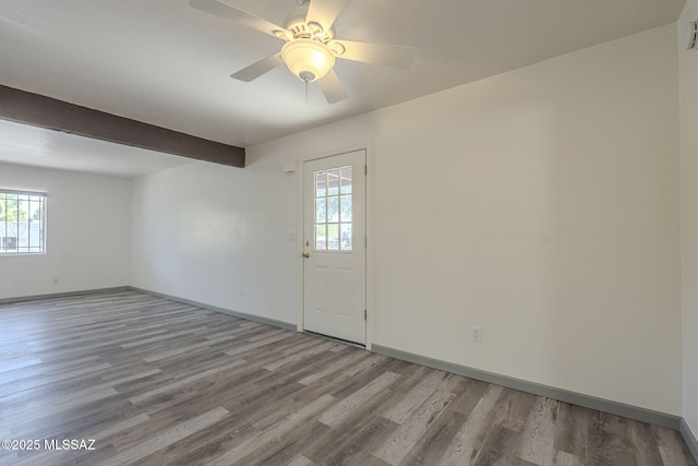 interior space with beam ceiling, a healthy amount of sunlight, and wood-type flooring