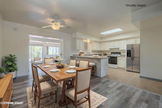 dining space with ceiling fan and light hardwood / wood-style flooring