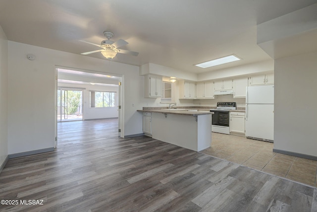 kitchen featuring a kitchen bar, white cabinets, kitchen peninsula, and white appliances