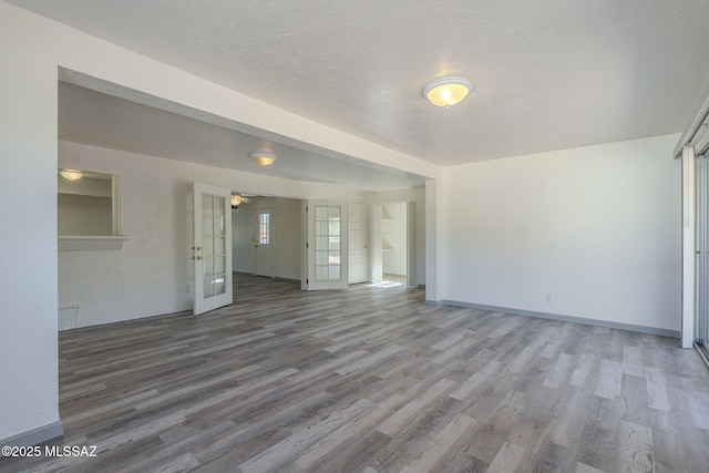 unfurnished living room featuring hardwood / wood-style floors, a textured ceiling, and french doors