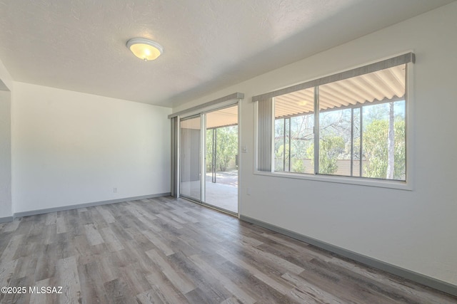 unfurnished room featuring light hardwood / wood-style floors, a wealth of natural light, and a textured ceiling