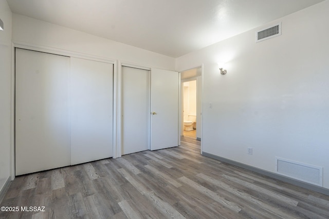 unfurnished bedroom with multiple closets and light hardwood / wood-style floors