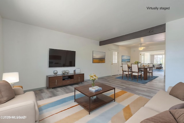 living room with ceiling fan, beam ceiling, and light hardwood / wood-style flooring