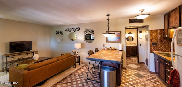 kitchen with pendant lighting, a breakfast bar, light tile patterned floors, and wooden counters