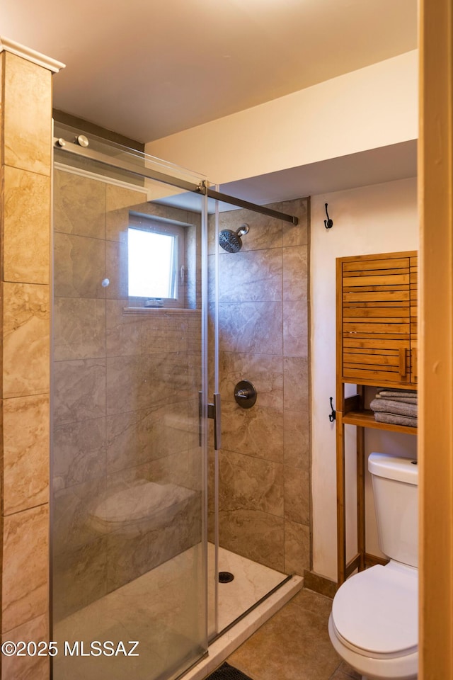 bathroom with tile patterned floors, toilet, and a shower with shower door