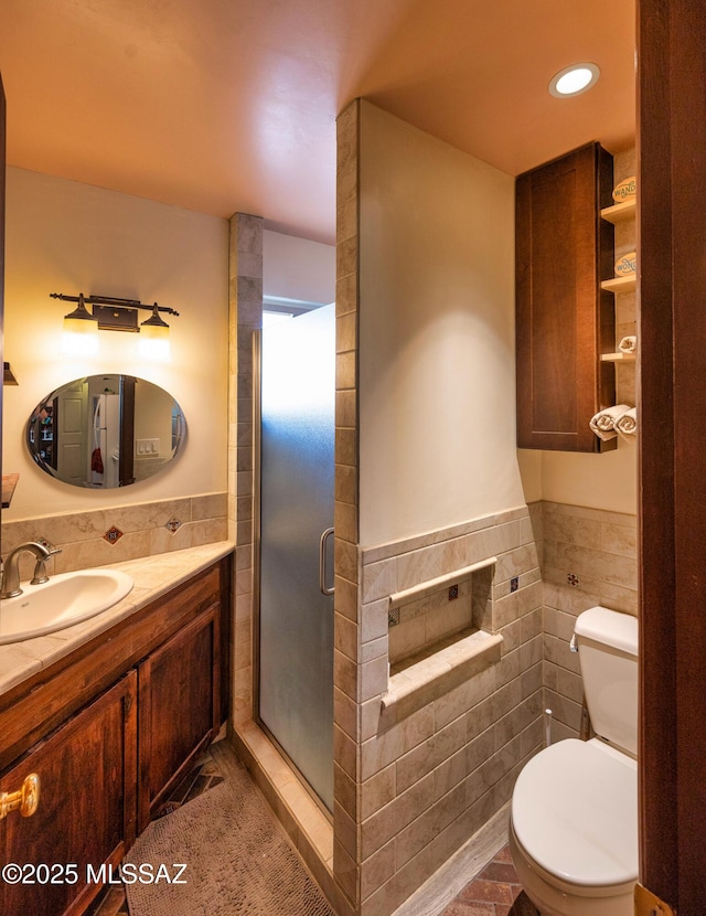 bathroom featuring toilet, vanity, tile walls, and walk in shower