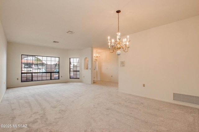 empty room featuring light carpet and a chandelier