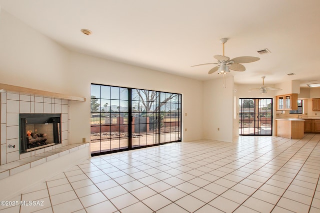 unfurnished living room featuring a fireplace, light tile patterned floors, and ceiling fan