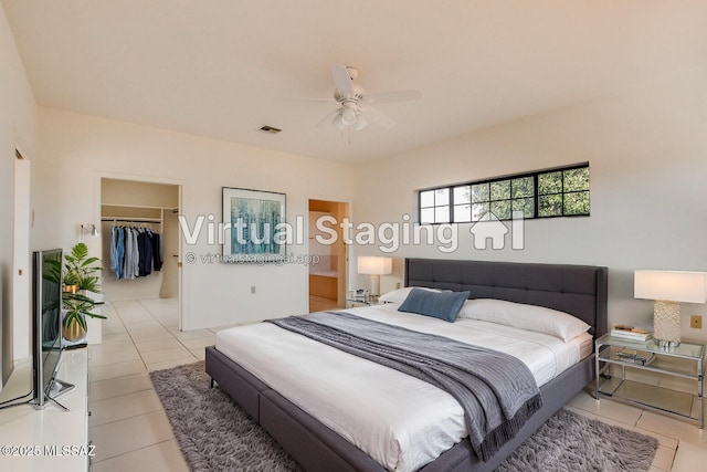 tiled bedroom with a walk in closet, ceiling fan, and a closet