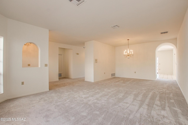 carpeted spare room with a chandelier