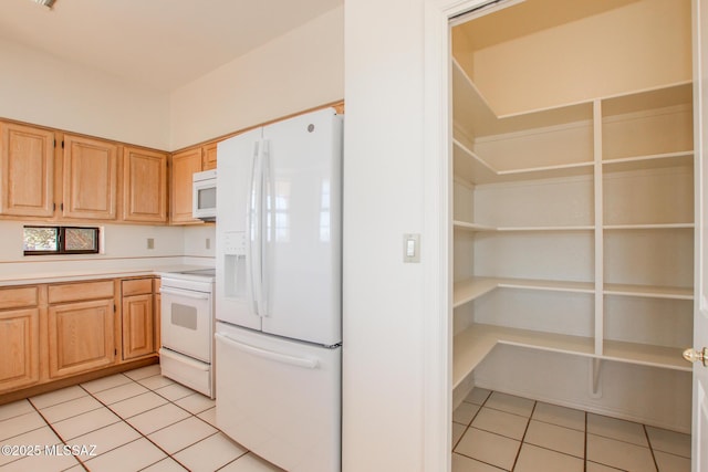 kitchen featuring light tile patterned floors, white appliances, and light brown cabinets