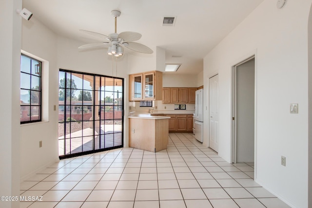 kitchen with light brown cabinets, white refrigerator, sink, ceiling fan, and light tile patterned floors