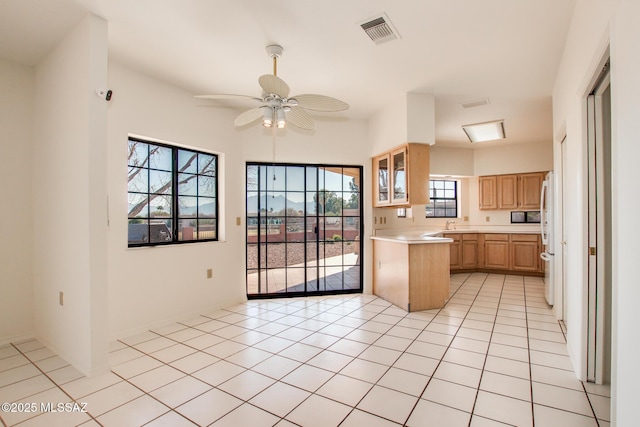 kitchen with light brown cabinetry, white fridge, ceiling fan, and light tile patterned flooring