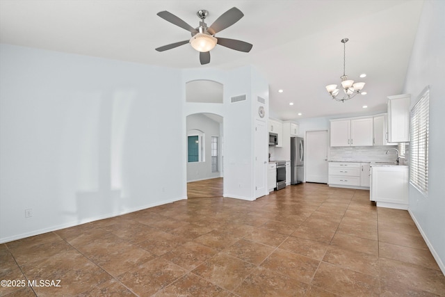 kitchen with pendant lighting, appliances with stainless steel finishes, backsplash, white cabinetry, and ceiling fan with notable chandelier