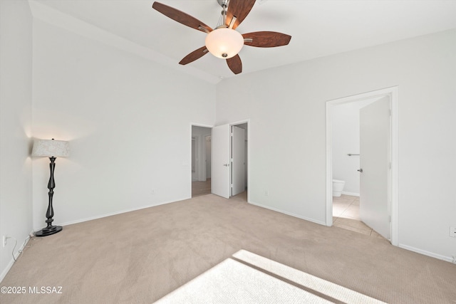 unfurnished bedroom featuring ceiling fan, light colored carpet, and connected bathroom