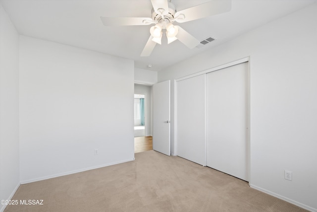 unfurnished bedroom featuring light carpet, a closet, and ceiling fan