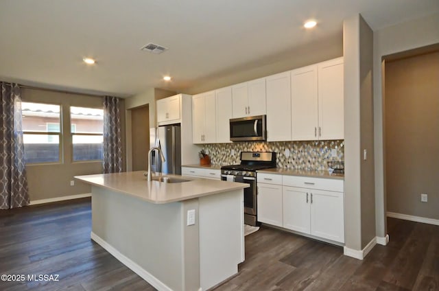 kitchen featuring stainless steel appliances, sink, white cabinetry, and an island with sink