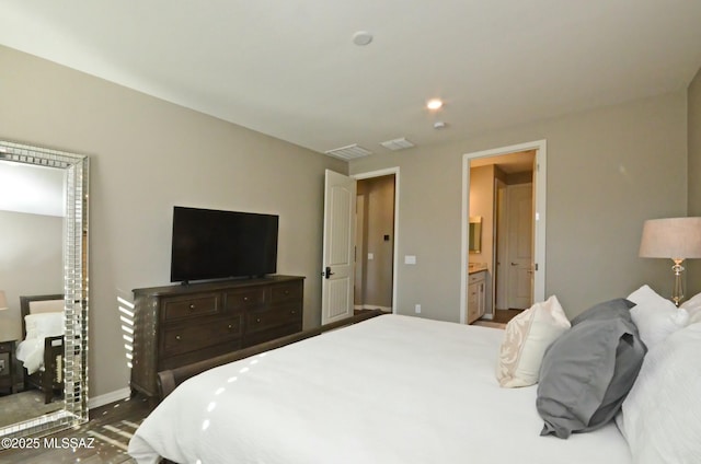 bedroom featuring dark wood-type flooring and ensuite bath