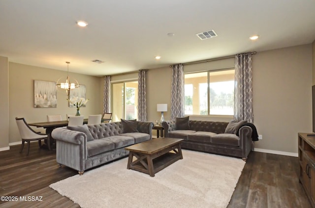 living room with a healthy amount of sunlight, dark wood-type flooring, and a notable chandelier