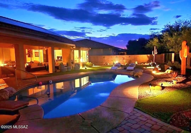 pool at dusk with a patio area