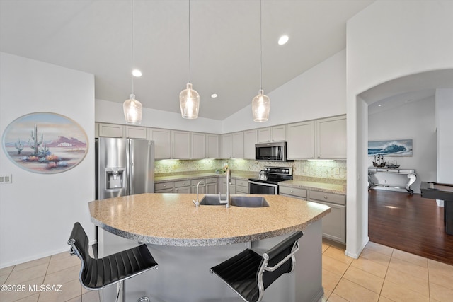 kitchen featuring light tile patterned flooring, appliances with stainless steel finishes, decorative backsplash, and sink