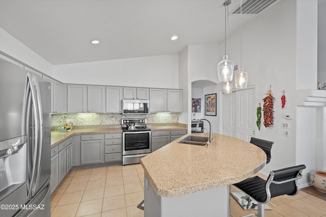 kitchen with gray cabinets, appliances with stainless steel finishes, tasteful backsplash, decorative light fixtures, and sink