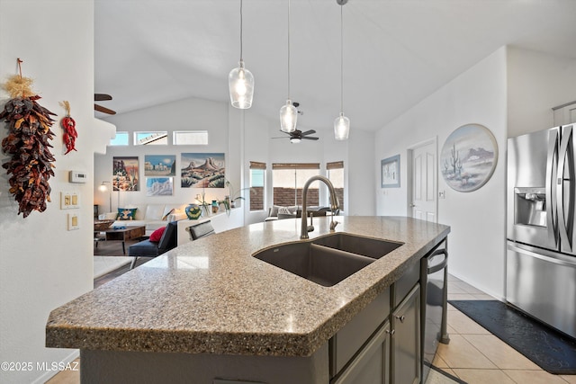 kitchen featuring ceiling fan, vaulted ceiling, a center island with sink, sink, and stainless steel fridge