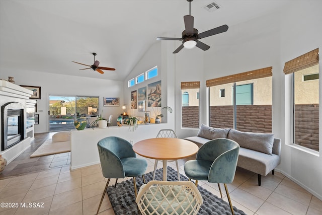 tiled dining area with ceiling fan and high vaulted ceiling