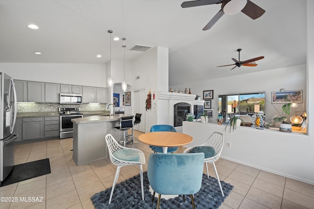 tiled dining space featuring ceiling fan and high vaulted ceiling