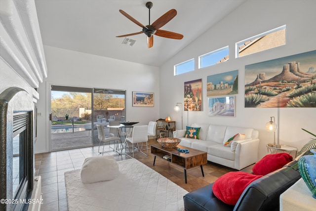 tiled living room with ceiling fan and high vaulted ceiling