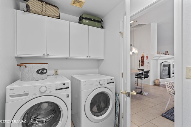 laundry area with washing machine and dryer, cabinets, and light tile patterned floors