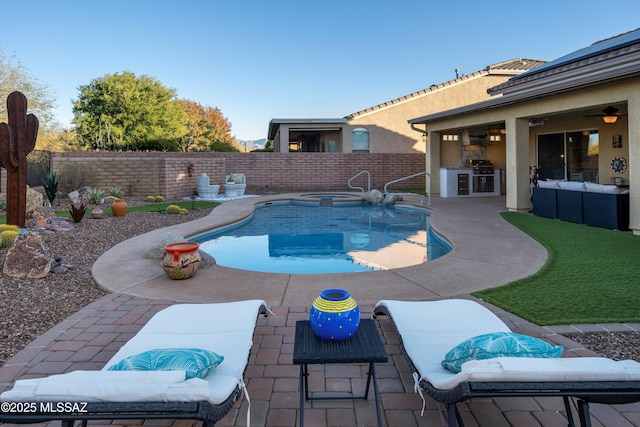 view of pool with a patio area, a grill, a jacuzzi, and exterior kitchen