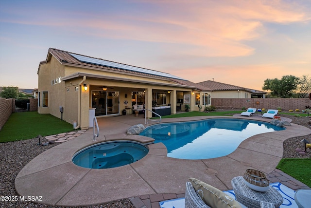 pool at dusk featuring a patio and an in ground hot tub