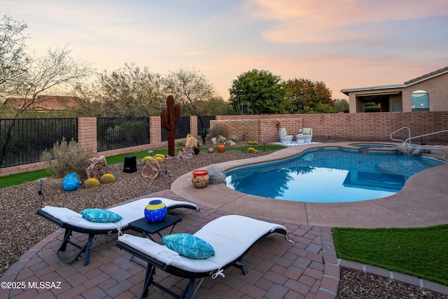 pool at dusk with an in ground hot tub and a patio