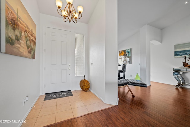 foyer featuring lofted ceiling, a chandelier, and light wood-type flooring