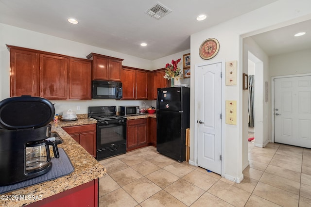 kitchen with black appliances, light tile patterned flooring, and light stone countertops