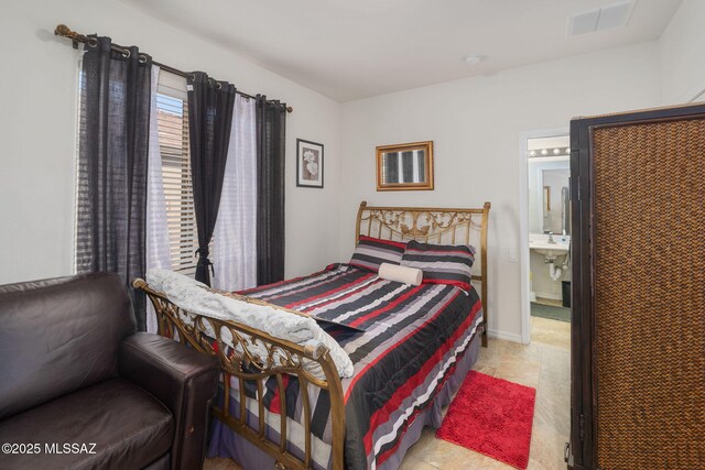 tiled bedroom featuring ensuite bath and sink