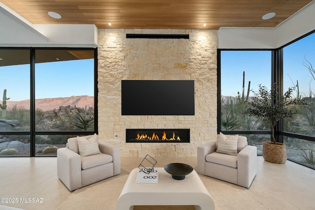 tiled living room featuring a stone fireplace and wooden ceiling