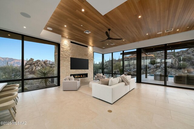 kitchen featuring sink, light tile patterned floors, light stone counters, wooden ceiling, and a large island with sink