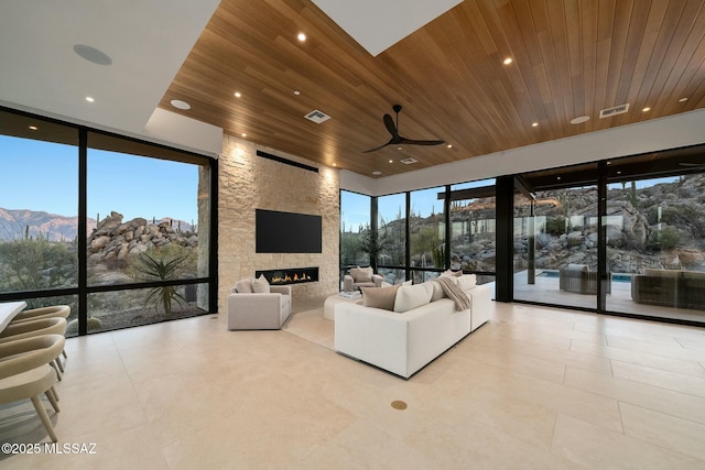 unfurnished living room with a stone fireplace, plenty of natural light, wooden ceiling, and a mountain view