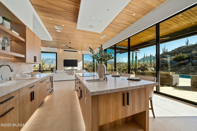 kitchen with light tile patterned floors, an island with sink, sink, and wooden ceiling