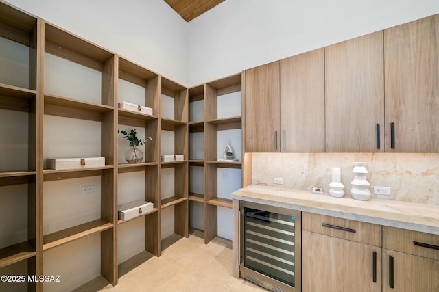 interior space with light stone countertops, light brown cabinets, wine cooler, and backsplash