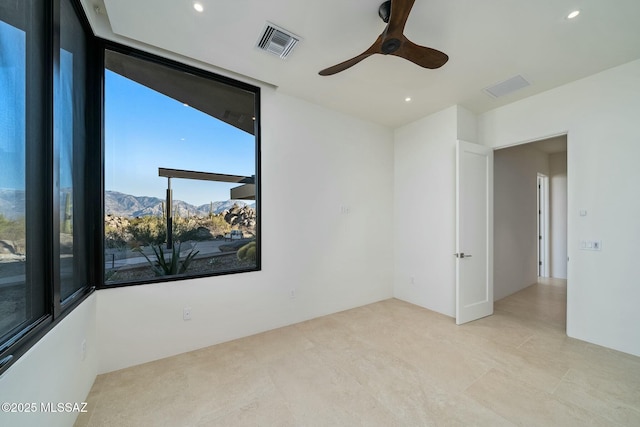 unfurnished room featuring a mountain view and ceiling fan