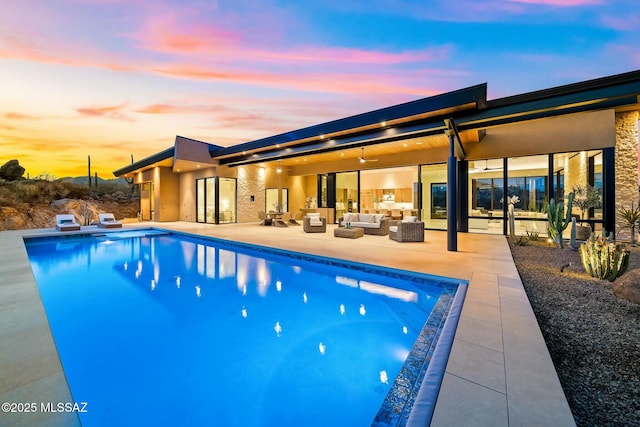 pool at dusk featuring an outdoor hangout area and a patio