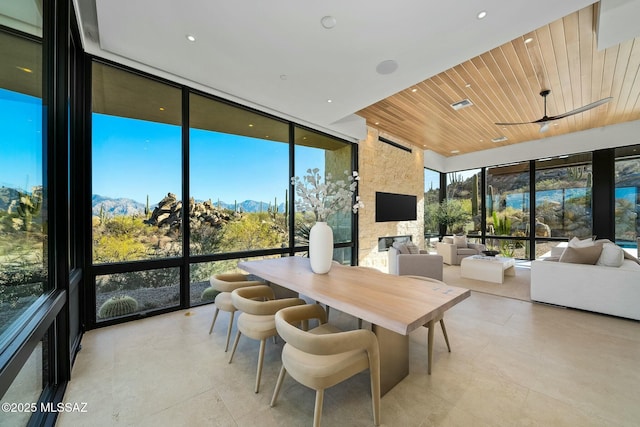 sunroom featuring a mountain view, a healthy amount of sunlight, and wood ceiling