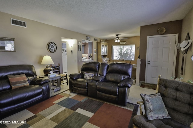 living room with ceiling fan and a textured ceiling