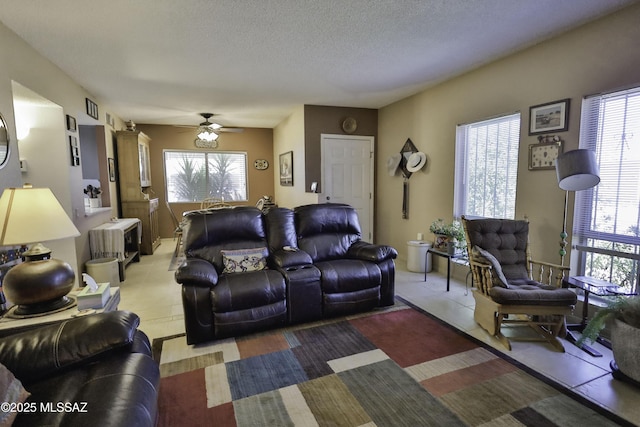 living room featuring ceiling fan and a textured ceiling